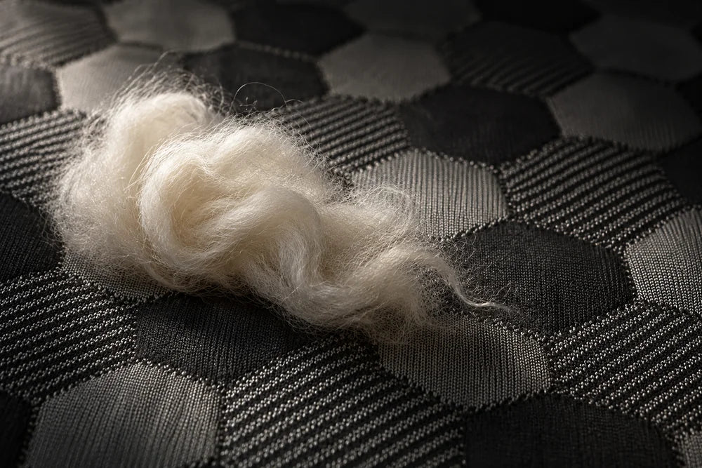 A wisp of New Zealand Joma Wool resting on the Artisan’s black and grey hexagon jacquard top