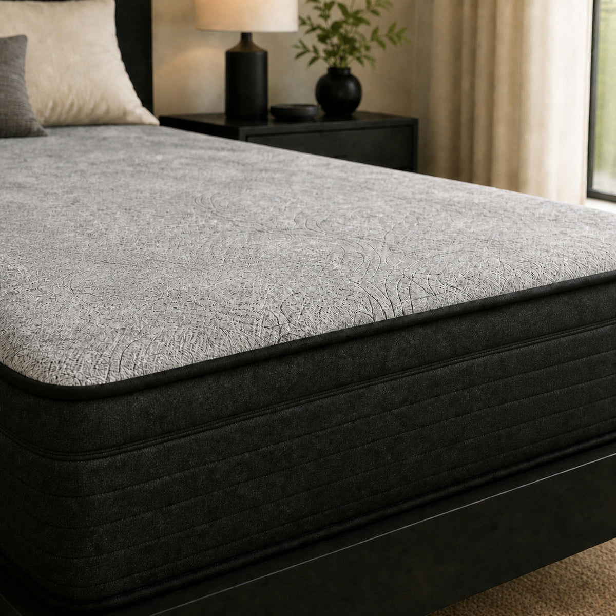 Close-up of the Studio mattress circular quilted comfort top, black piping, and charcoal channelled sidewall