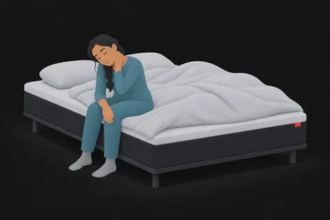 A tired woman sitting on the edge of her bed rubbing her neck