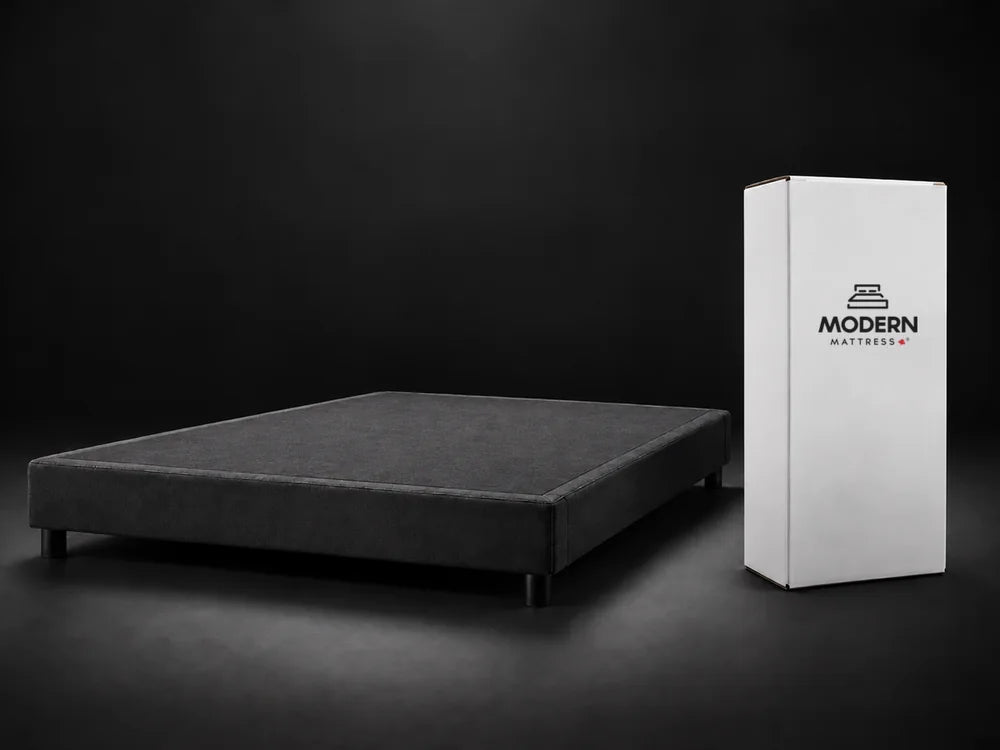 The closed white Modern Mattress box standing beside an empty bed base